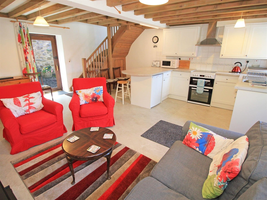 Integrated living area showing settee and easy chairs with breakfast bar and kitchen units