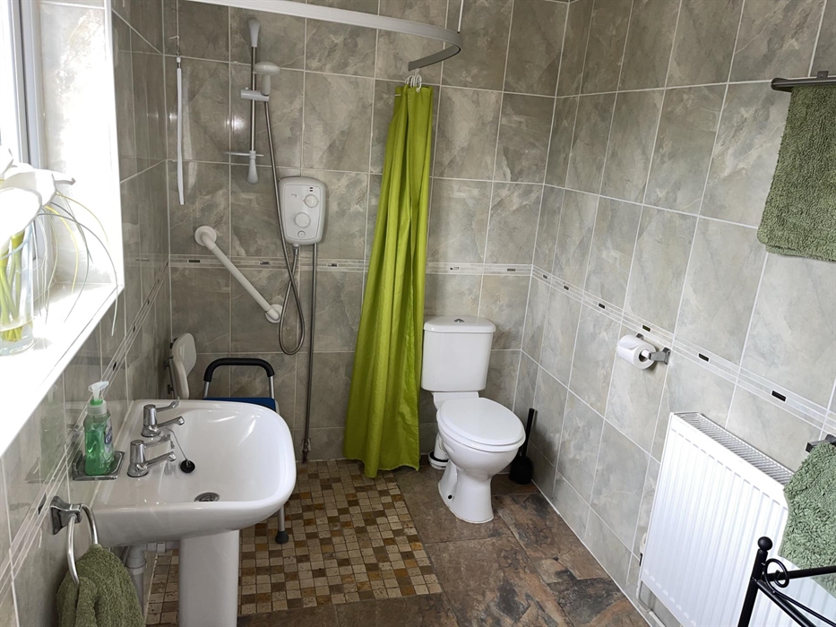 Pedestal sink, shower, shower curtain, height adjustable shower chair, toilet, towel rack and radiator. A raised toilet seat on a frame available on r