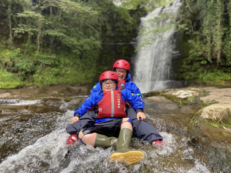 Young boy and instructor in waterfall and stream