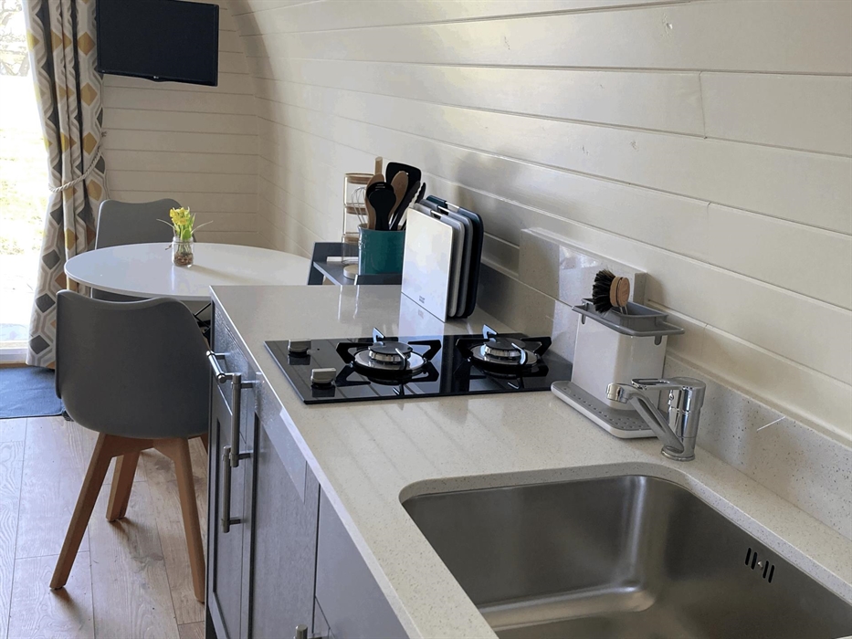 displaying table and chairs, sink, hob with all the utensils for self catering stay