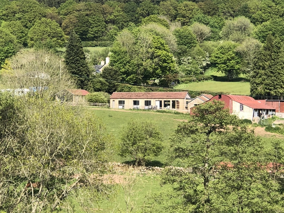 A view across the Glyn valley looking at the three Welsh Marches cottages, with Chepstow Park Woods behind.