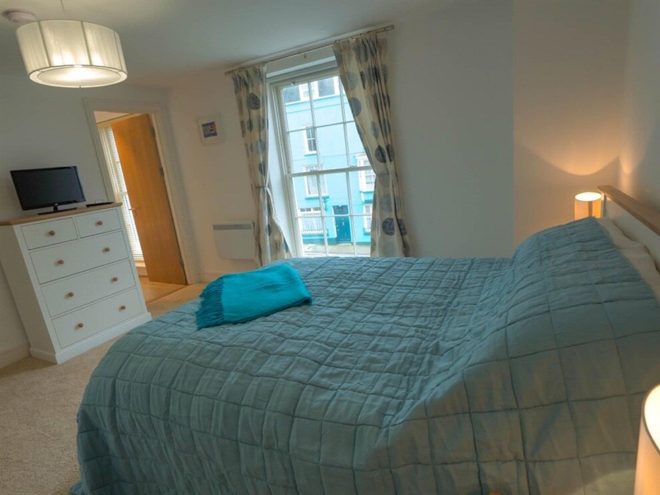 King bedroom with chest of drawers and TV and showing window view with door to en-suite bathroom