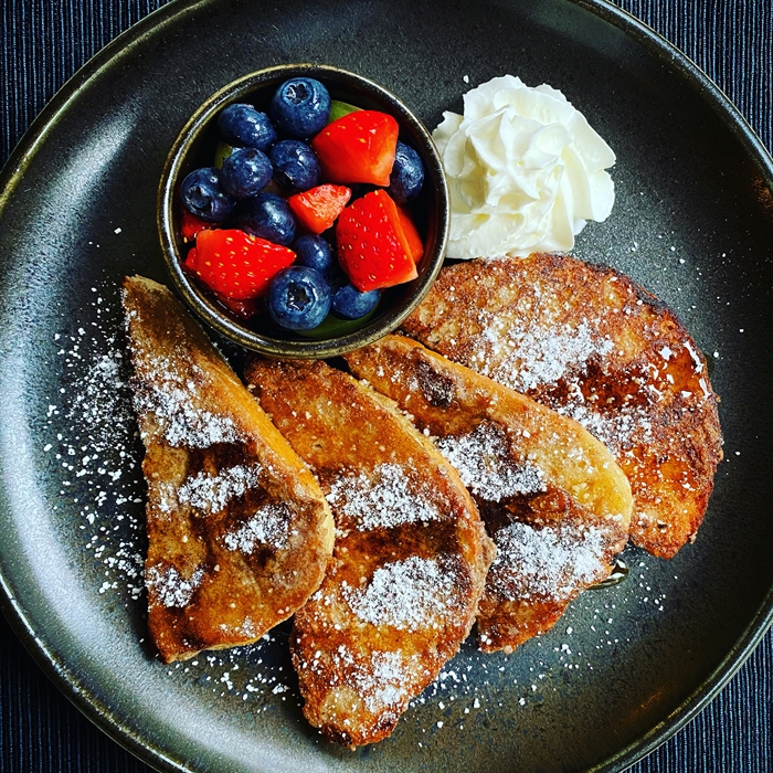 French toast with fruit on a black plate