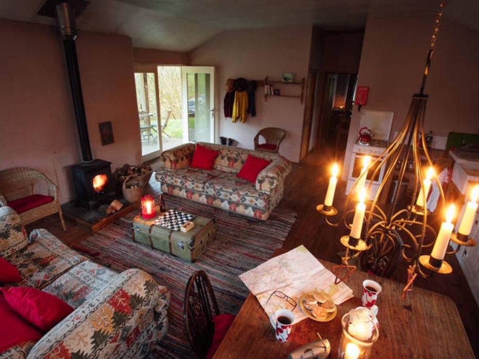 Comfy sofas, dining table, kitchen area, woodburner & candles. Just a step through the French doors and  you are on the veranda with views and the sou