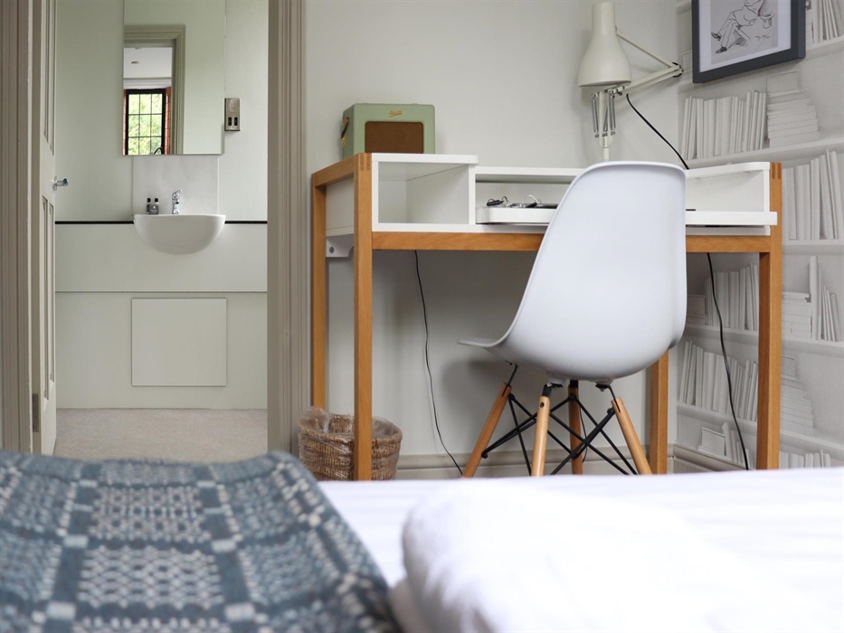 A view over a single bed showing a desk and chair and the entrance to a bathroom