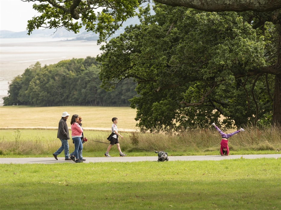 A family with a dog take a walk around the grounds of Penrhyn Castle and one of the children is doing a cartwheel
