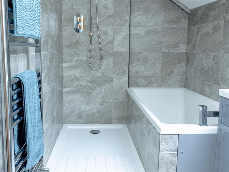 Bath with separate waterfall shower and heated towel rail.