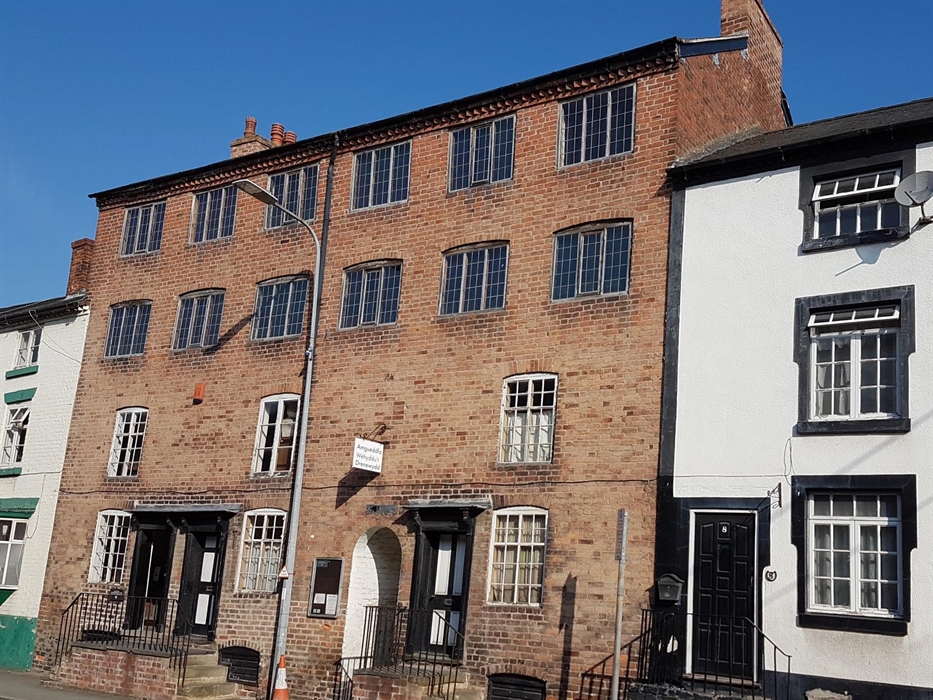 The building was originally six two-room cottages with 2 loom floors above. Each window had a loom. Now the cottages relate the woollen industry story