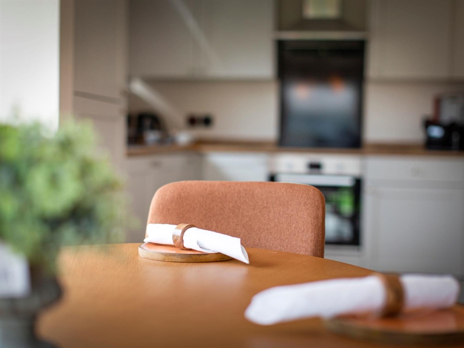 Dining table and chair with napkins and kitchen in background