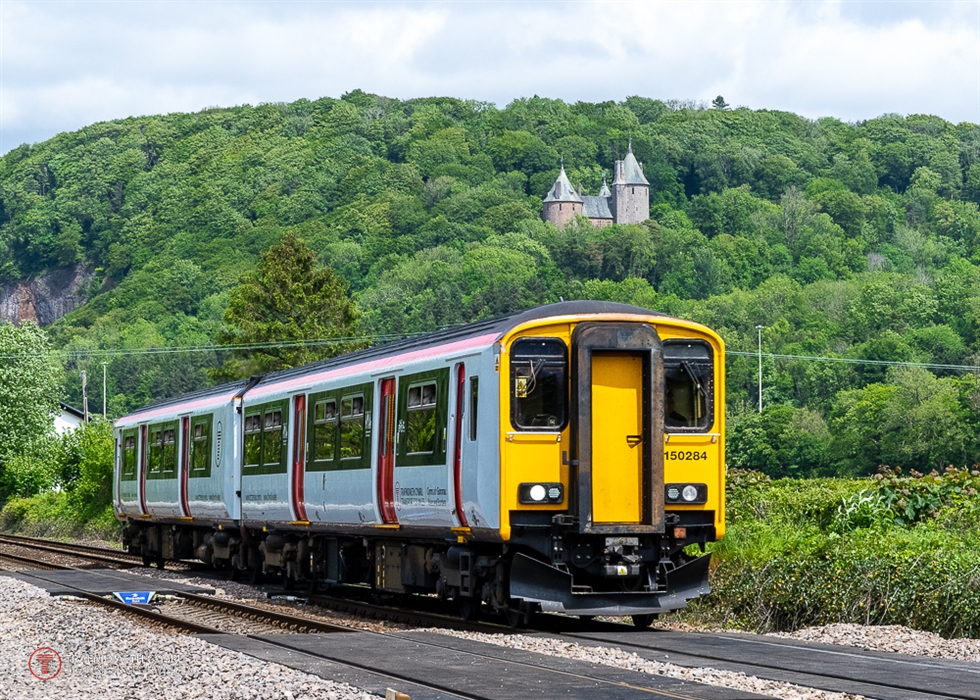 A train passing by a castle on a hill