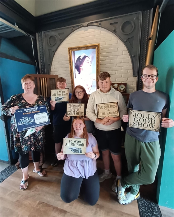 Mixed group exploring puzzles in a Victorian-style escape room at Mansion of Mystery.