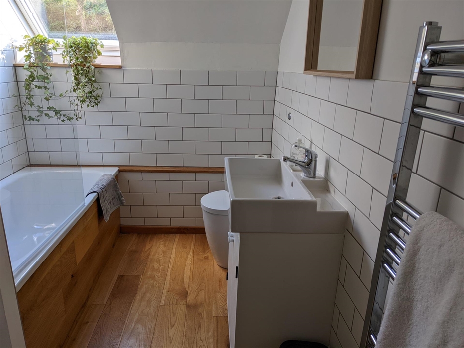 Yr Hal Bathroom with bath and shower over, wash basin, loo and heated towel rail. Lovely warm oak floor.