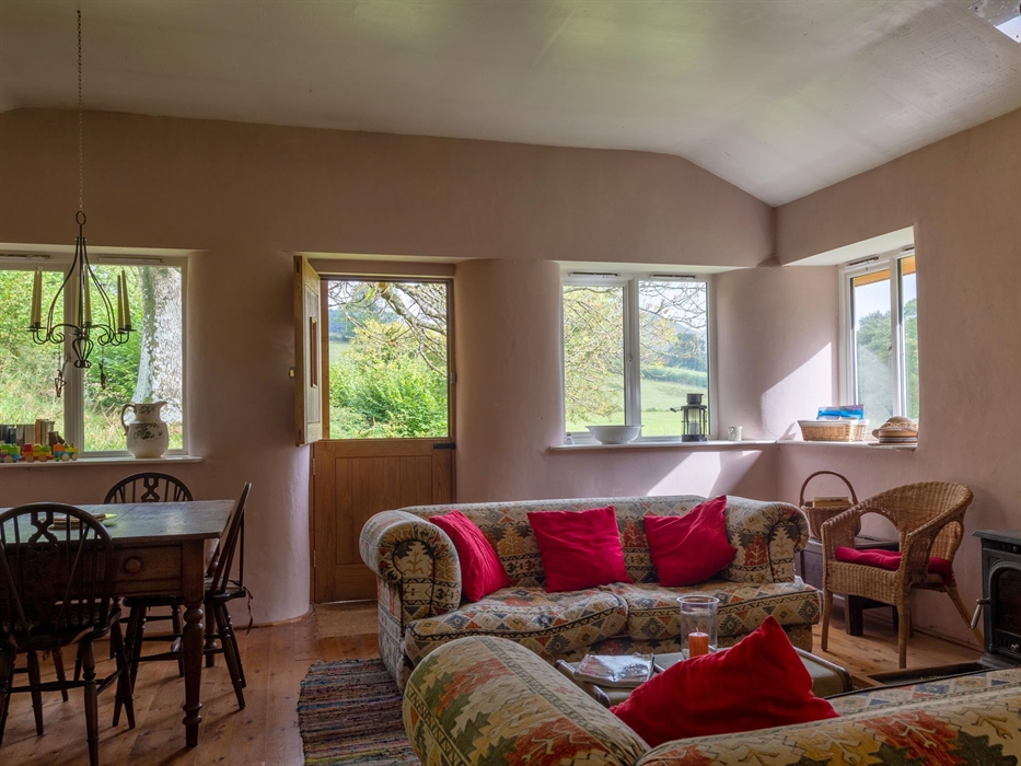 Large sitting room with dining table, wood burner, French doors to veranda with far reaching views.