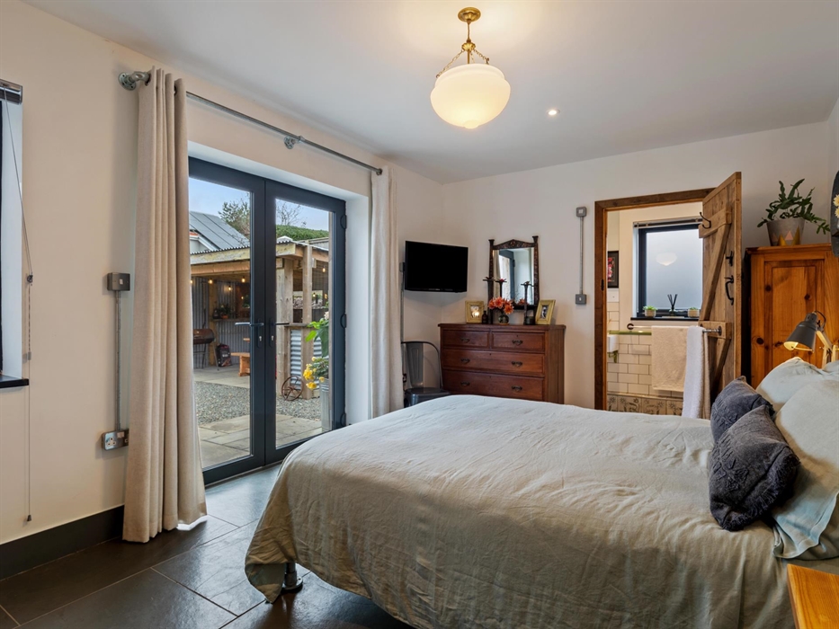 on the ground floor with french doors leading to patio and covered BBQ area, wall mounted smart TV, period central lampshade, cottage style wooden doo