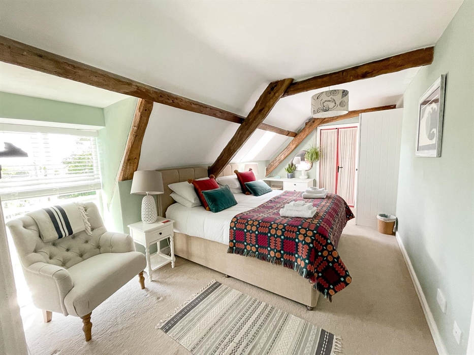 A superking bedroom with welsh tapestry blanket in red, orange and petrol blue. Seadog and stone self catering holiday let