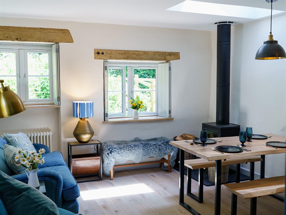 YR Ffald Cottage luxurious living space with velvet sofa, sheepskin rugs on bench, live edge dining table and benches for 4 people, windows with shutt