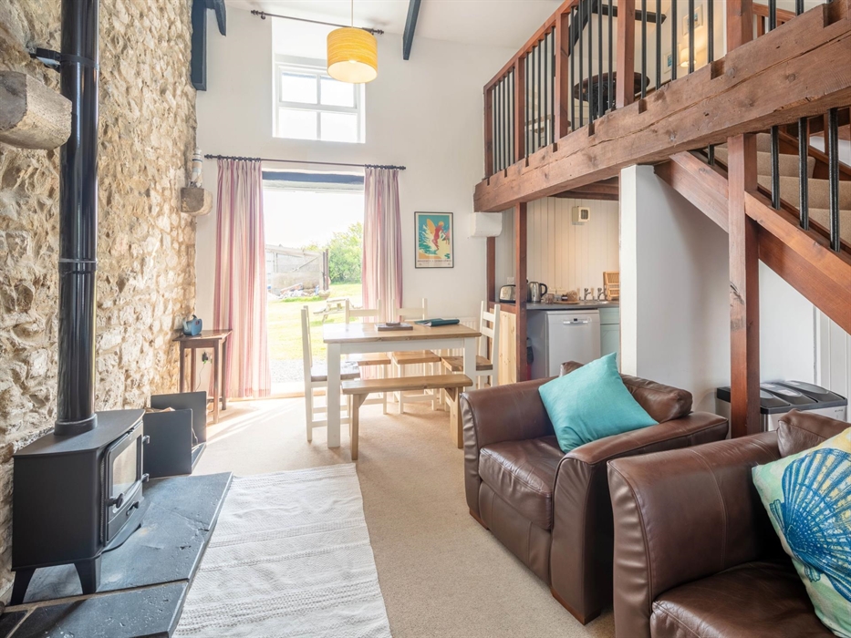 Double height living room with wood burner and French windows onto shared field