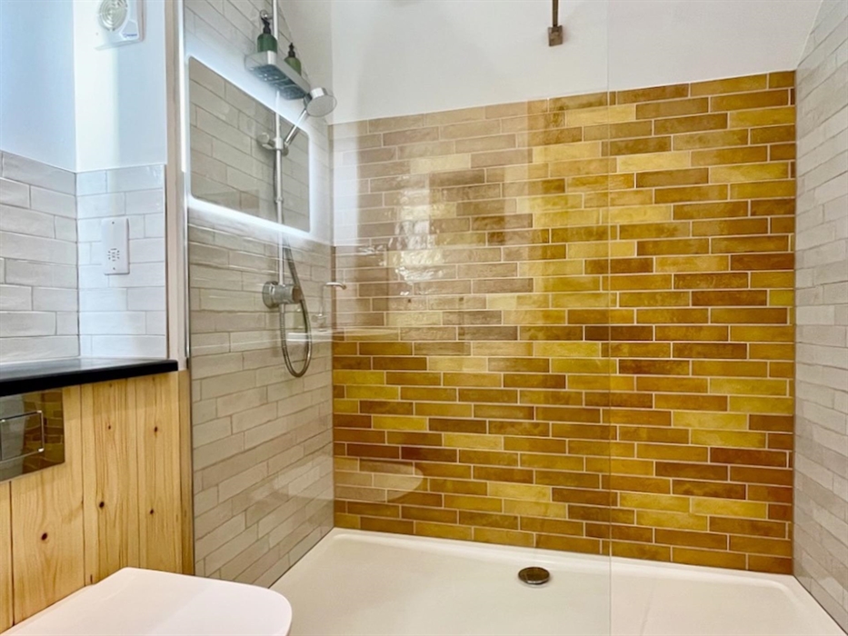 A bright modern shower room with glass screen and colourful tiles