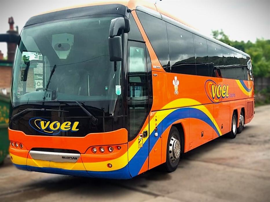 Voel Coaches Neoplan Tourliner Executive Coach in bright orange with a yellow and blue wave ribbon livery.