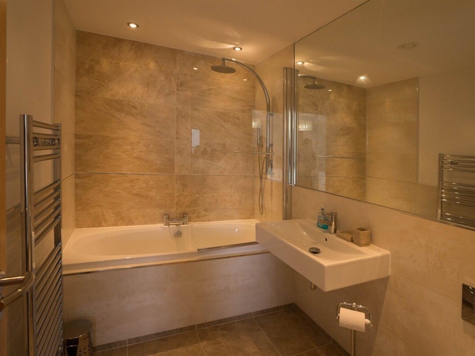 En-suite bathroom showing shower over bath with sink and towel rail