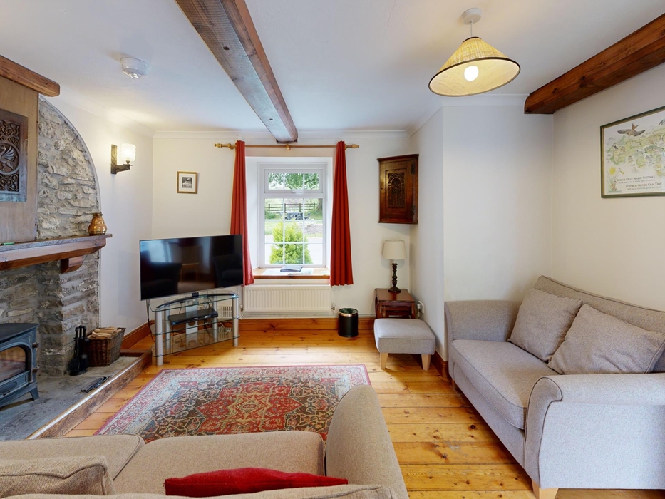 Traditional lounge with two sofas, log burner, wooden floors, and cottage-style decor.
