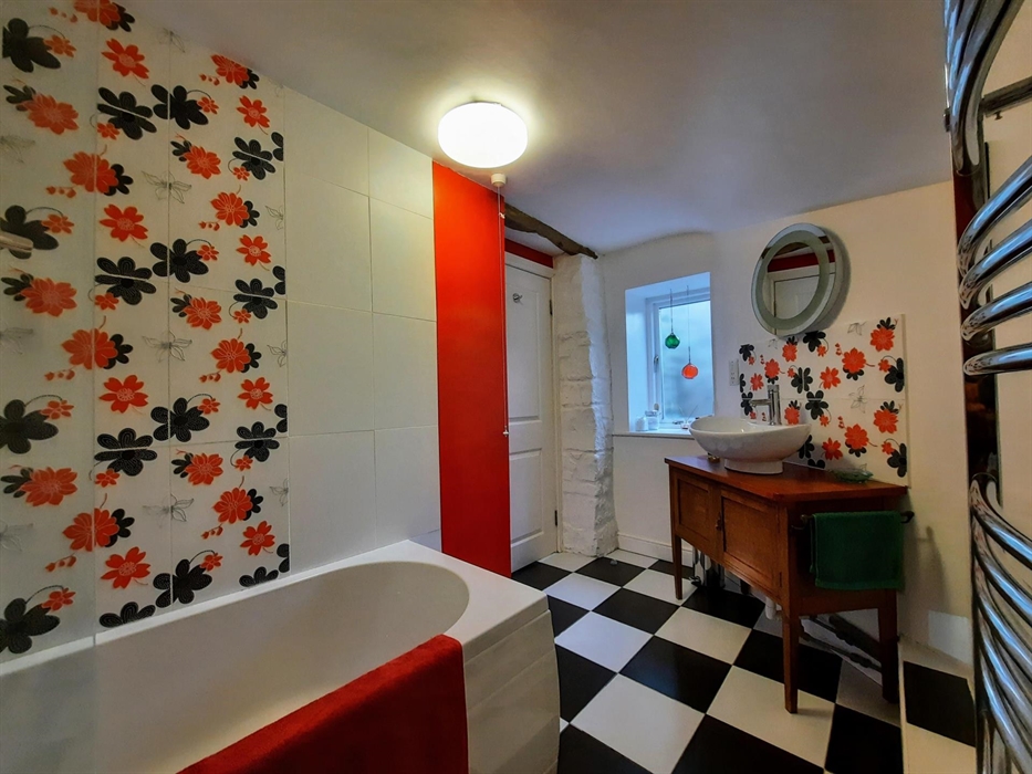 Cwt Mochyn cottage family bathroom with bath and overhead shower, and cabinet with large washbasin