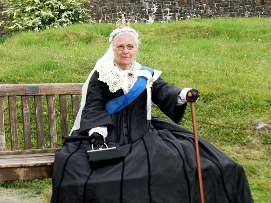 Re-enactor sitting on a bench dressed as Queen Victoria