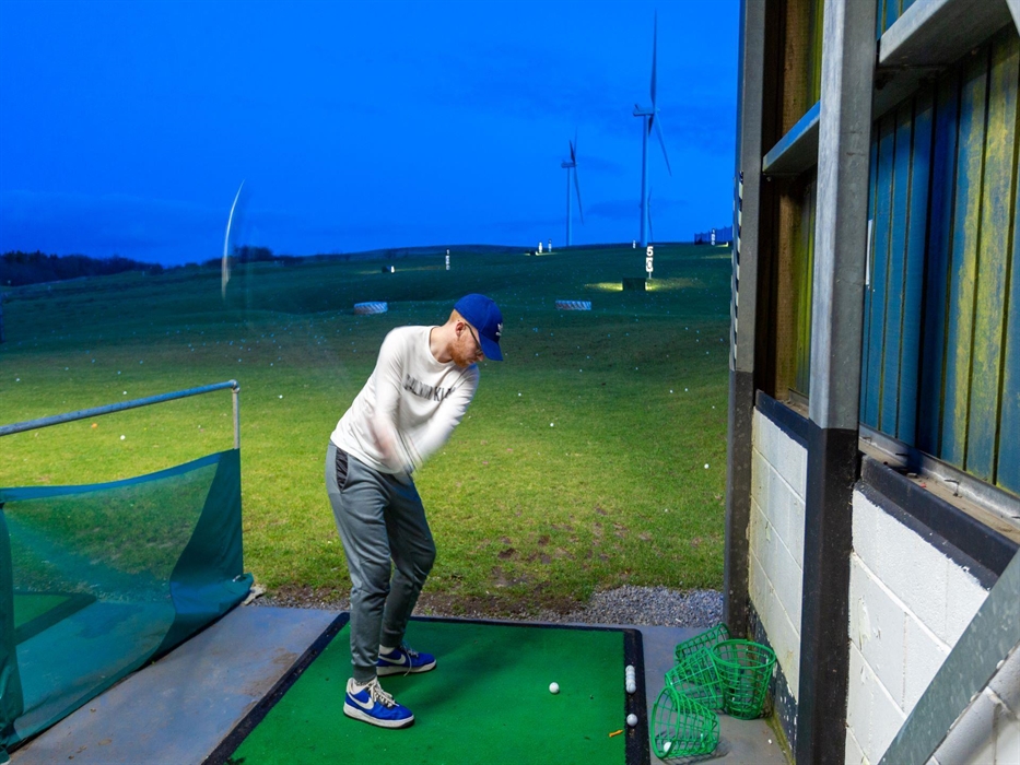 Golfers hone their skills at the driving range.