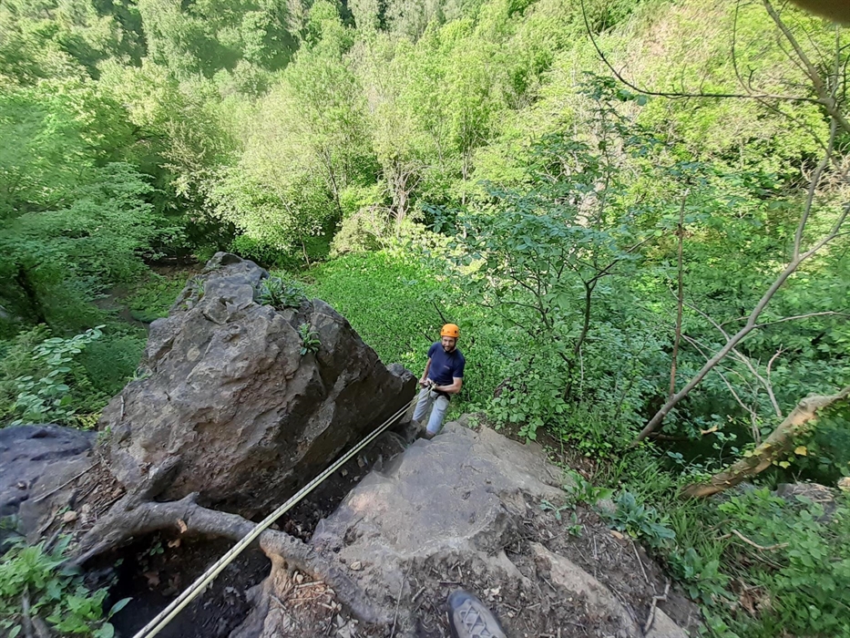 Man attached to rope abseiling down cliff