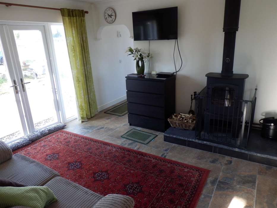 Lounge area showing the 43" tv, the multifuel fire, 3 seater sofa bed and patio door leading out to the patio and Jacuzzi garden area