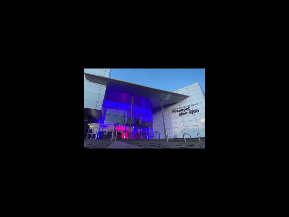 The theatre building lit up with blue and pink lights.