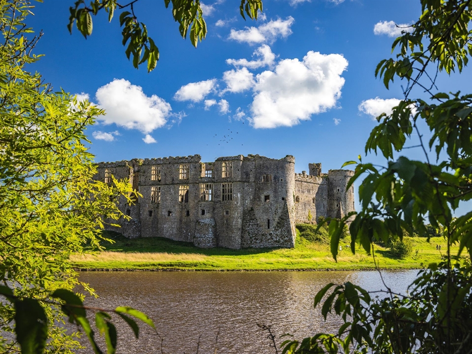 View of Carew Castle through some trees showing some pond
