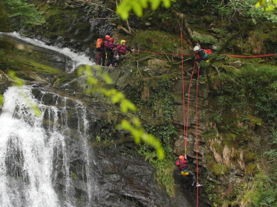 Bearded men adventures canyoning down a waterfall, snowdonia