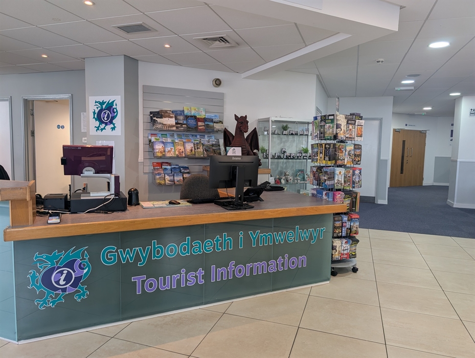 Reception desk inside Llandudno Tourist Information Centre with visitor guides, maps and local gifts on display.