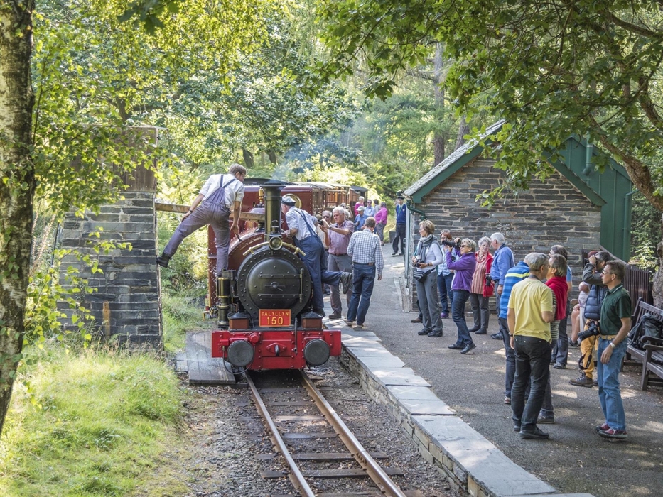 The locomotive takes water at Dolgoch Station with passengers onlooking
