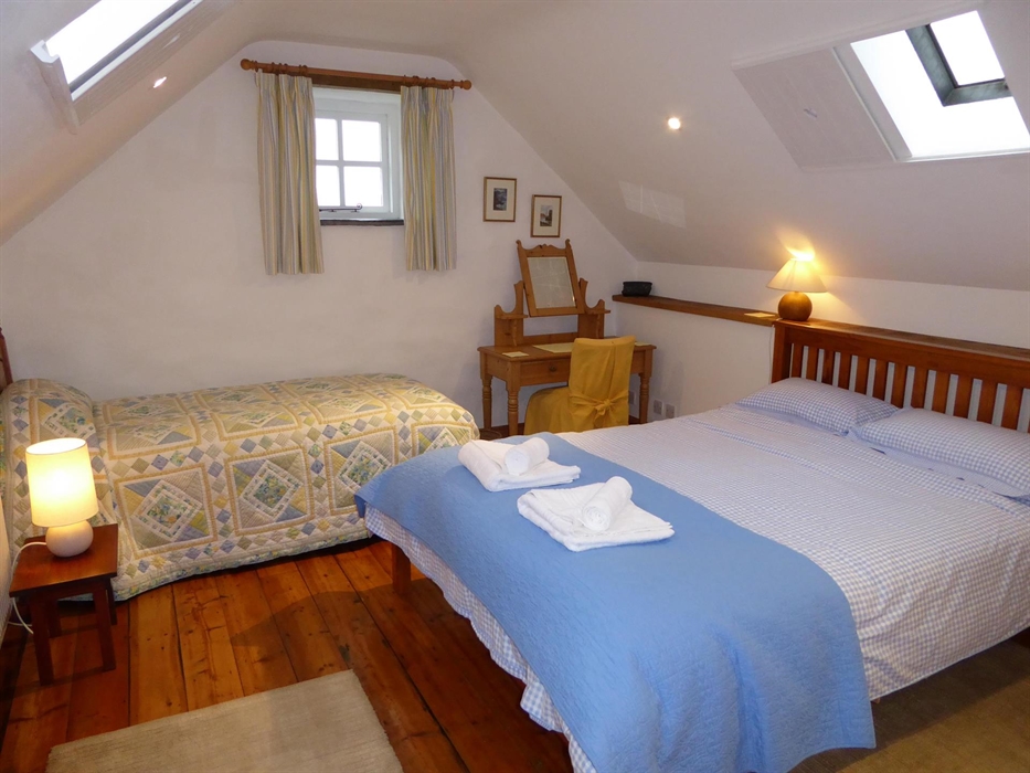 The large bedroom in Ty Canol has plenty of room for a king size bed and a single bed. Sliding shutters on the roof-lights provide an ingenious way to