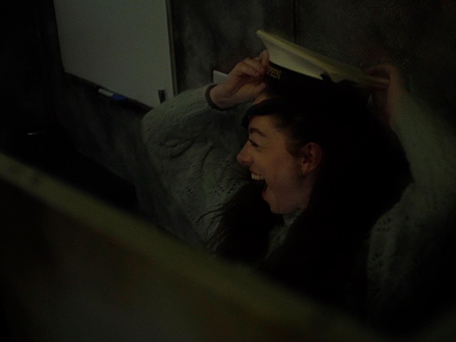 A girl is pictured inside an escape room having just found the captains hat, placing it on her head.
