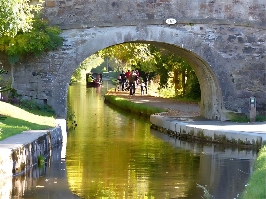 Scene of one of Llangollen canal's historic stone bridges (46) With a view of canal walkers and one of Llangollen Wharf's horse drawn boats in the dis