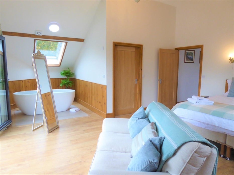 Bedroom 1 (upstairs) with superking size bed or 2x single beds, sofa, smart TV and free standing bathtub. There is a covered balcony which looks over