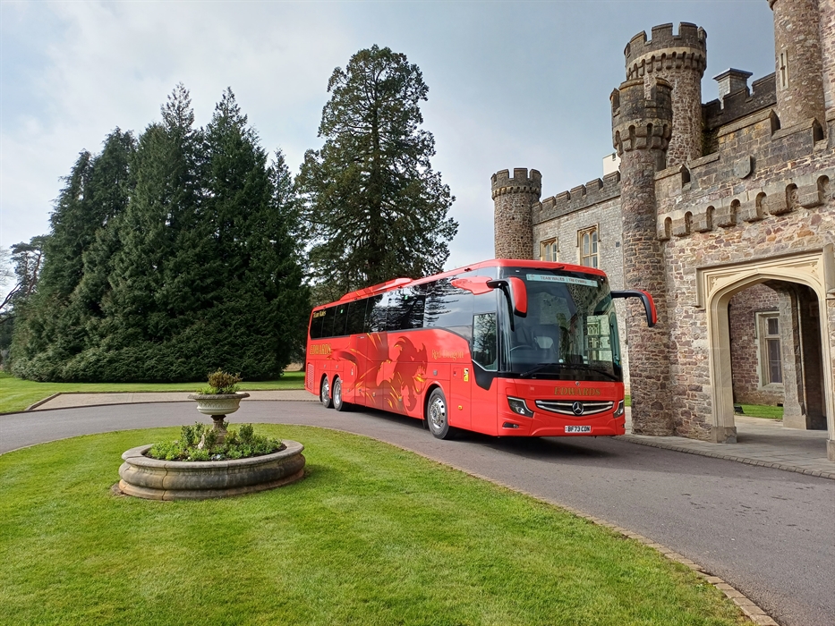 A red coach parked outside castle entrance