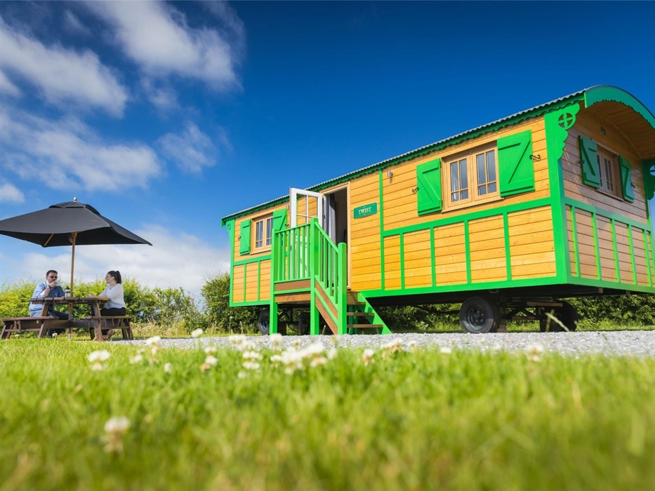 Couple enjoying a coffee at a table with umbrella next to Showman's Wagon