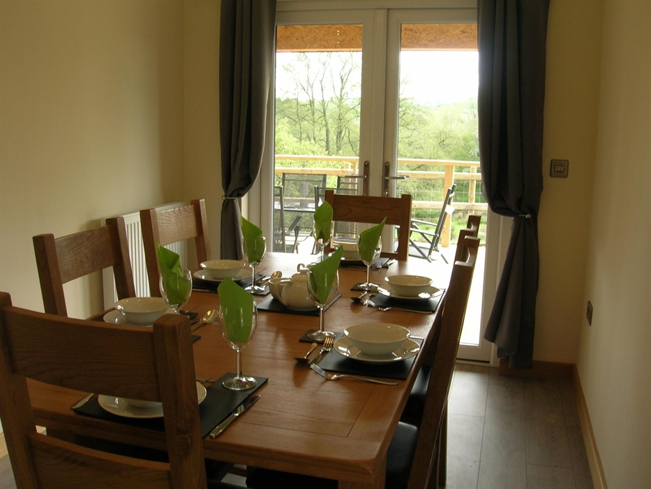 The dining table leads out to covered decking area containing Hot Tub.