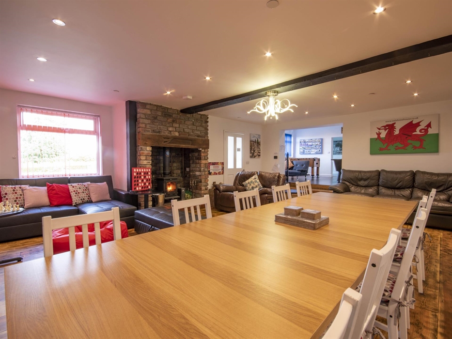 Welsh Row House with large living room and dining area with log ingle nook fireplace. 
 Leading through to games room.  Wooden floor and seating area