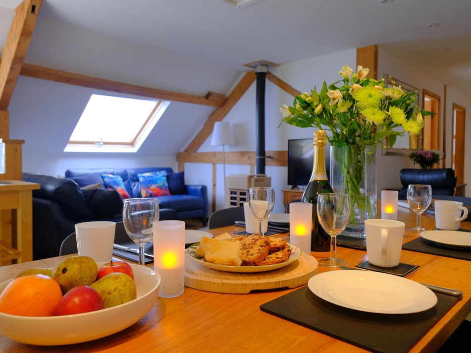Table with cakes, fruit, flowers and fizz.