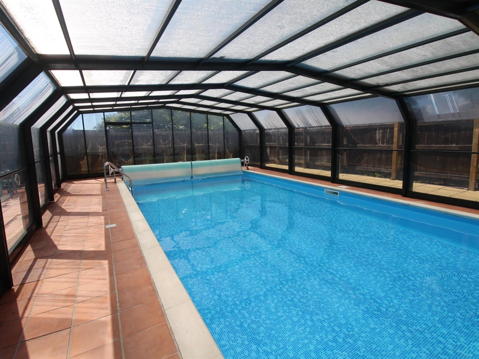 Photo of the heated swimming pool at Ysgubor Degwm on the Llyn peninsula. Swimming pool with blue tile liner with a retractable roof and terracotta ti