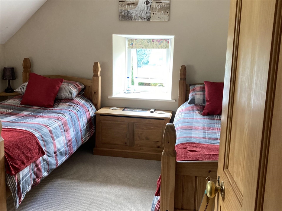 A twin room with a wash basin within Moorland, and a private toilet and over the bath shower off the landing. Window over looking the garden at Llwyn