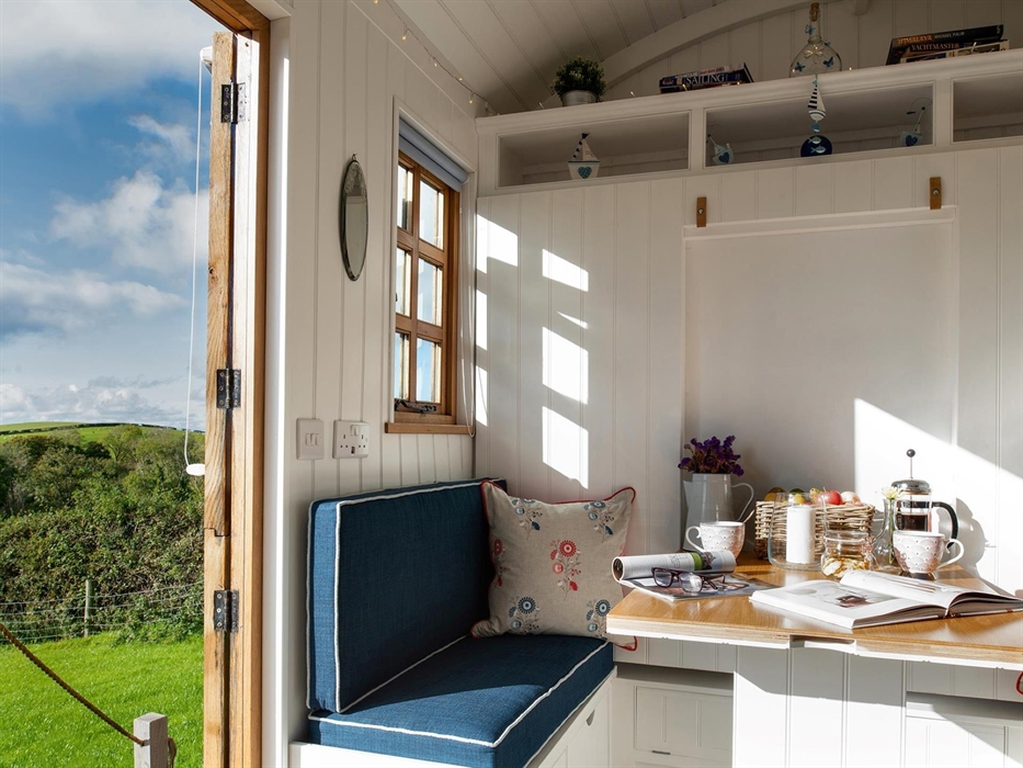 This shows the table and seating in the hut.  It is very bright and sunny inside, the table is has coffee and biscuits, perfect to sit and read a maga