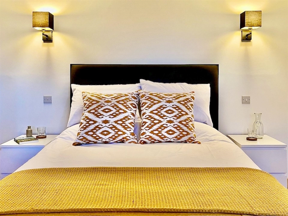 A bed with a colourful throw and decorative cushions