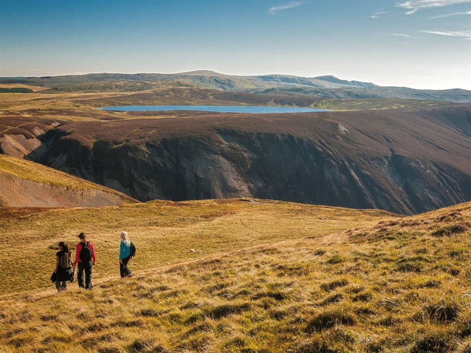 Three female walkers descending Foel Fadian just off Glyndwr's Way with Glaslyn in the background