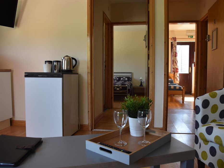 Communal space with kitchenette, looking into bedroom one and bedroom two